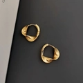 Elegante gouden gedraaide creolen met getextureerde afwerking op een grijze achtergrond - 925 zilver / Goud