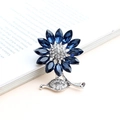 Elegant silver sunflower brooch with dark blue crystals on an open vintage book page - Aqua