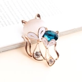 Detailed view of fox brooch with pink opal stone and blue crystal on book page - Gold