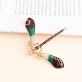 Elegant vintage dragonfly brooch with green and pink enamel wings on an open book - Coffee