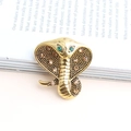 Golden cobra brooch with green and amber crystals on a book background - Gold