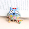 Light blue enamel owl brooch with red bow and floral patterns on a branch base - Colorful