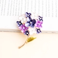 Elegant purple rhinestone flower cluster brooch with gold base on a vintage book - Violet