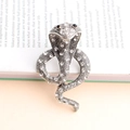 Broche serpent cobra argentée scintillante avec cristaux blancs sur fond de livre - Blanc