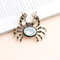 Macro detail of vintage gold crab brooch featuring a large opal and green rhinestones - Antique Gold Green