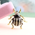 Elegant rhinestone beetle brooch with black enamel inlay next to a velvet gift box - White AB