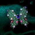 Luxurious butterfly brooch with green micro-pave crystals and colorful gems on green satin - Colorful