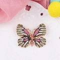 Creatieve vlinderbroche met roze en groene kristallen op goudkleurig metaal - Oranje Edelsteen Gradiënt