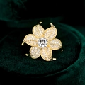 Luxury gold flower brooch with sparkling zircon petals on a green velvet background - White