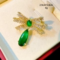 Detail einer goldenen Schleifenbrosche mit weißen Zirkonia und grünem Tropfenanhänger - Grüner Schleifenstil (B741)