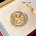 Close-up of gold-plated smiley face brooch with pearls and zircon pavé detailing - B894