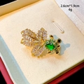 Nahaufnahme einer goldenen Goldfischbrosche mit lila Zirkon und grünen Wassertropfensteinen - Grüner Goldfischstil (B844)