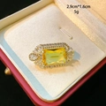 Detail view of a 2.9cm clover brooch with a yellow gemstone and rhinestone setting - Rectangular Style (D161) / Yellow