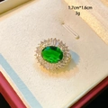 Close-up of green oval gemstone brooch with white zircon inlay on gold metal base - Green