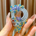 Elegante spilla a ghirlanda di fiori con zirconi multicolore tenuta nella mano - Stile Ghirlanda Interamente in Zirconia (B1762)