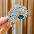 Elegant silver feather brooch featuring a pear-cut blue sapphire and sparkling zircons - Blue Feather Style (B1824)