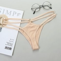Nude thong with thin double straps and a metal ring detail, flat lay on a grey background - Nude