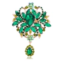 Macro shot of vintage gold brooch with teardrop emerald crystals and rhinestone details - Gold Tone Green Crystal