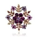 Elegant gold flower brooch with purple rhinestones and crystal accents on white background - Purple Gold