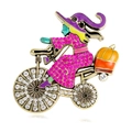 Whimsical Halloween witch on bicycle brooch with orange pumpkin and purple rhinestones - Pink Purple Dress Style (B104-B)