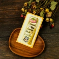 Macro detail of a yellow travel-themed metal bookmark with golden tassel and wood backdrop - Travel the world Style (T01042564)