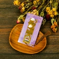 Detail view of a hollow gold metal bookmark with purple backcard and brown tassel - T01042627