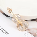 Spilla a forma di violino dorata con cristalli lucenti su uno sfondo minimalista - Oro