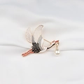 Close-up of golden crane brooch with enamel details and drop pearl on white silk fabric - Flying Pose Style (XZ2203-1)