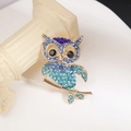 Detailed close-up of a blue rhinestone owl brooch on an elegant vintage gold base - Blue Gradient Style (XZ028)