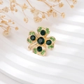 Detailed close-up of a four-leaf clover brooch with green crystals and gold-plated finish - Gold