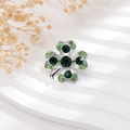 Detailed view of silver clover brooch with green rhinestones on white wavy background - Silver