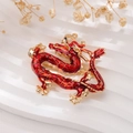 Close-up of a red enamel dragon brooch with gold edges on white textured background - Chinese Style Red Dragon
