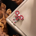 Macro detail of bow brooch featuring red rhinestones and dangling tassel charms - Silver with Red Zirconia