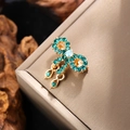 Detail of vintage gold bow brooch featuring green crystals and sparkling teardrop pendants - Gold with Green Stone