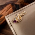 Detail of treble clef music brooch with white diamonds and purple teardrop gem - Gold & Purple Rhinestone Teardrop Style