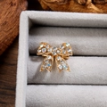Détail d'une broche nœud dorée avec strass multicolores et structure ajourée délicate - Or Blanc