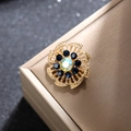 Primer plano de broche floral dorado con piedra holográfica y cristales azules - Base Dorada Piedra Azul