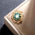 Vista macro del broche de flor dorada vintage con diamantes azules y piedra central irisada - Dorado / Verde