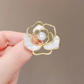 Detailed close-up of a gold flower brooch with white pearl and shell inlay held by hand - Camellia Flower Style (XZ5-373-121)