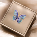 Close-up of golden butterfly brooch with blue rhinestones on silk jewelry box - Blue Gradient Butterfly Style (XZ5-341)