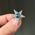 Spilla a stella d'argento con gemma blu e cristalli scintillanti tenuta in mano - Blu Argento