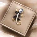 Detailed macro view of a luxury black enamel lizard brooch with grey crystal head and gold accents - Black Enamel Lizard Style (XZ20-047)