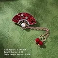 Detail view of fan-shaped brooch with red enamel, white rhinestones and gold tassel chain - Red