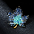 Golden maple leaf brooch with gradient blue rhinestones on black leather surface - Maple Leaf Blue
