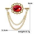 Makroaufnahme einer Vintage-Brosche mit rotem Edelstein, Goldrand und zwei Kettenfransen - Rot