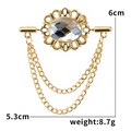 Makroaufnahme einer goldenen Vintage-Brosche mit ovalem Kristall und Metallquasten - Klarweiß