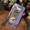 Close-up of golden metal bookmark with tassel and motivational quote on a wood tray - See Good In Everything Style (T01042312)