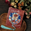 Detailed close-up of a blue hollow butterfly metal bookmark with tassels on a wooden tray - Blue Round Frame Butterfly Style (T01042308) / Blue