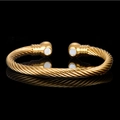 Goldener gedrehter Armreif mit zwei magnetischen Kugeln auf einem schwarzen Hintergrund - Kordel-Stil mit doppelten Magnetperlen (Gold, 2 Magnete) / Gold