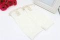 Detail of cream knitted boot cuffs featuring delicate lace trim and dual button accents - White